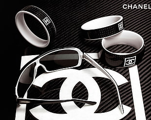three black-and-white Chanel bangles beside black sunglasses with white and black frame